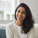 Close-up portrait of a smiling South Asian woman with warm, friendly expression.